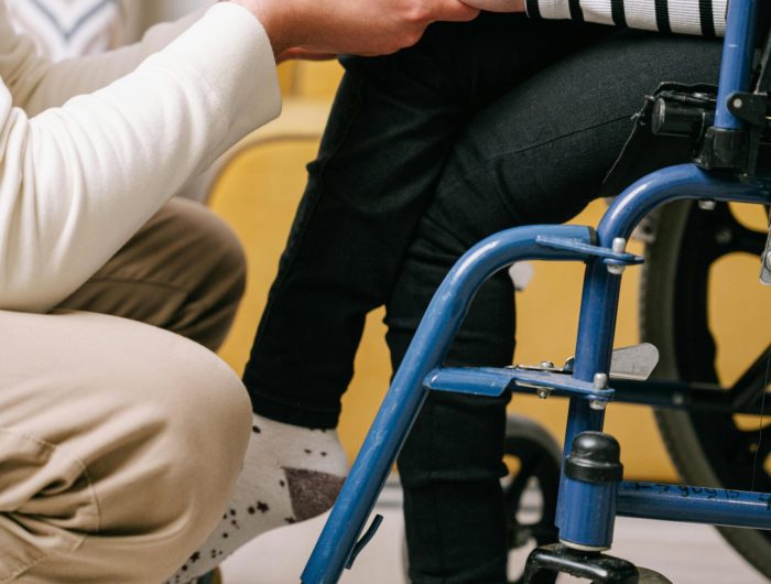 Supportive interaction between caregiver and wheelchair user, showing compassion.